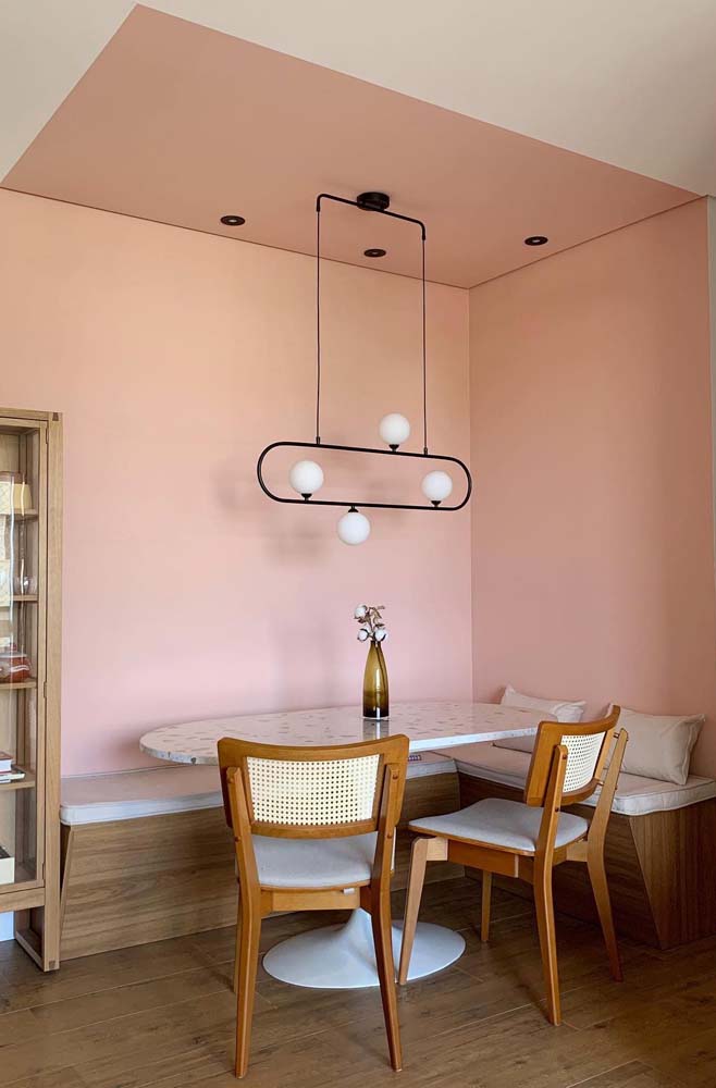 Pictura roz de pe pereti si tavan ajuta la delimitarea mediului de luat masa din acest colt german cu o masa ovala saarinen.